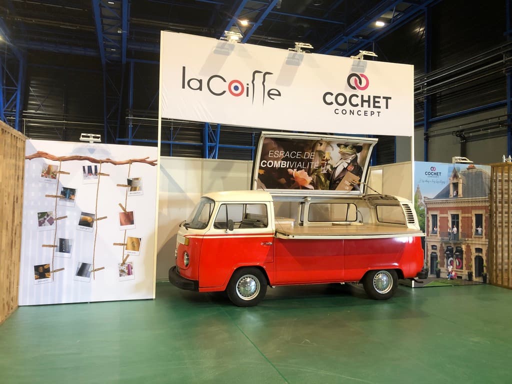 Combi VW rouge et blanc sur le stand La Coiffe Cochet Concept en salon professionnel avec comptoir en bois ouvert